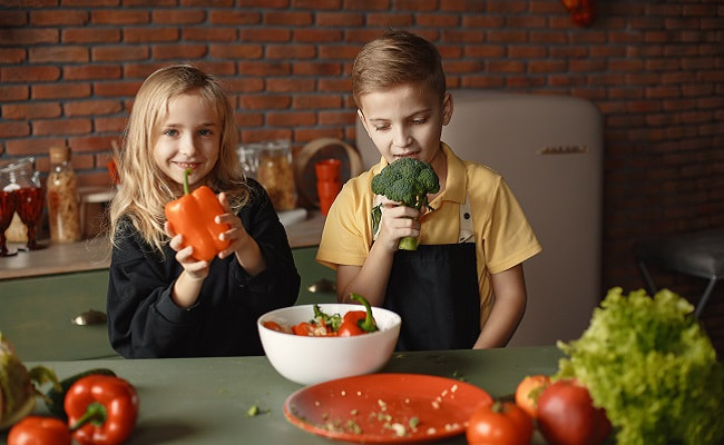 Two children holding vegetables